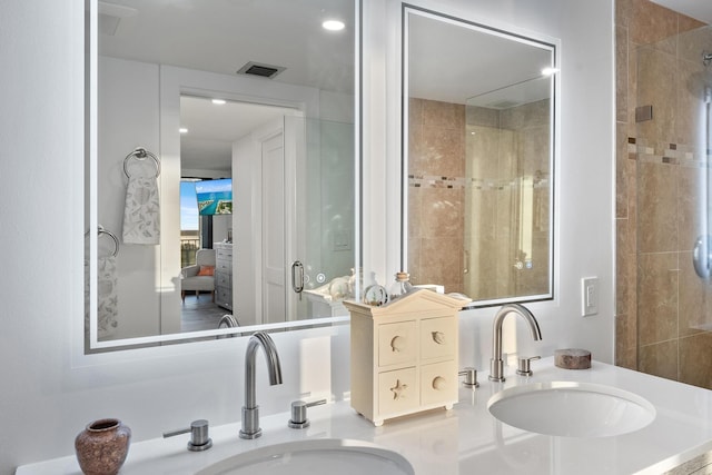 bathroom with a tile shower, visible vents, and a sink