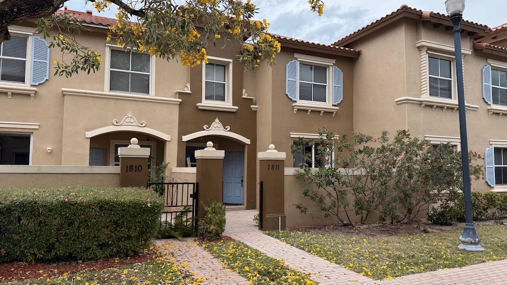 view of front of home with a tile roof, fence, and stucco siding