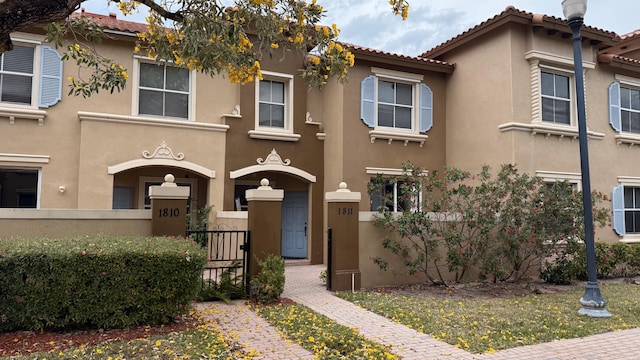 view of front of home with a tile roof, fence, and stucco siding