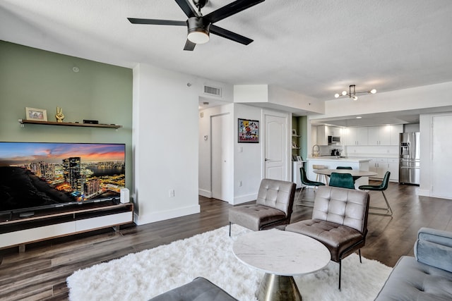 living room with visible vents, dark wood-type flooring, baseboards, a textured ceiling, and a ceiling fan