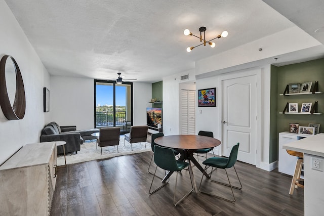 dining area with visible vents, ceiling fan with notable chandelier, a textured ceiling, dark wood-style floors, and baseboards
