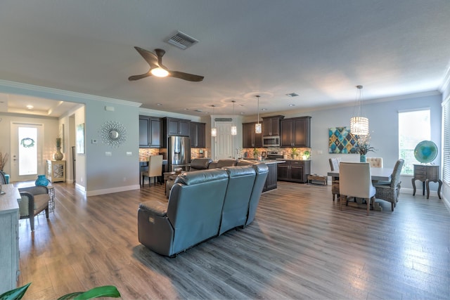 living room featuring visible vents, baseboards, dark wood-style flooring, and crown molding