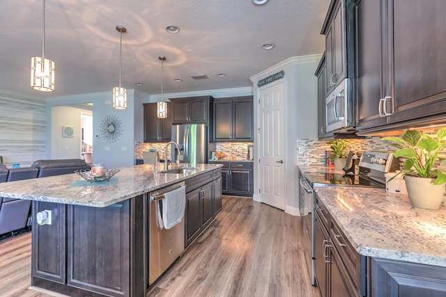 kitchen featuring a sink, wood finished floors, appliances with stainless steel finishes, crown molding, and light stone countertops