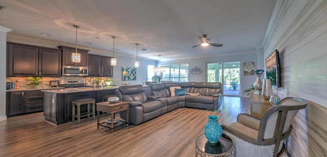 living area featuring visible vents, crown molding, ceiling fan, and wood finished floors