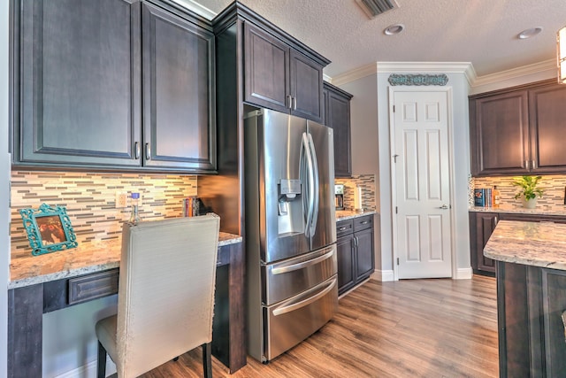 kitchen featuring wood finished floors, visible vents, stainless steel refrigerator with ice dispenser, and light stone countertops