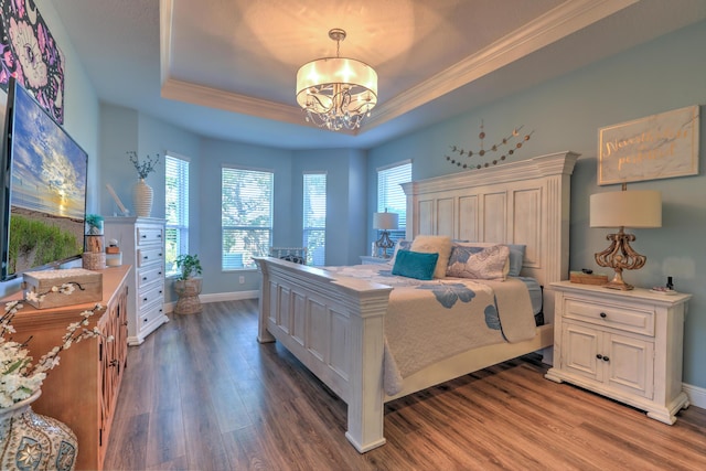 bedroom with wood finished floors, baseboards, crown molding, a raised ceiling, and a chandelier