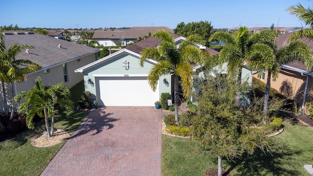 view of front of property featuring decorative driveway, an attached garage, and stucco siding