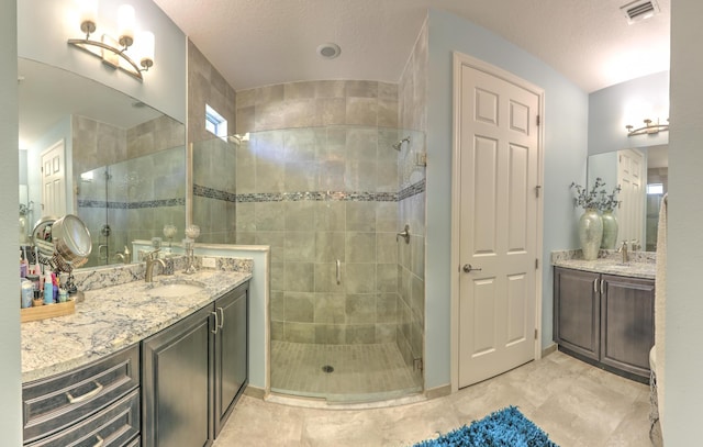 bathroom with visible vents, a textured ceiling, vanity, and a tile shower