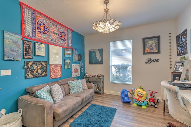 living room with a chandelier, baseboards, and wood finished floors