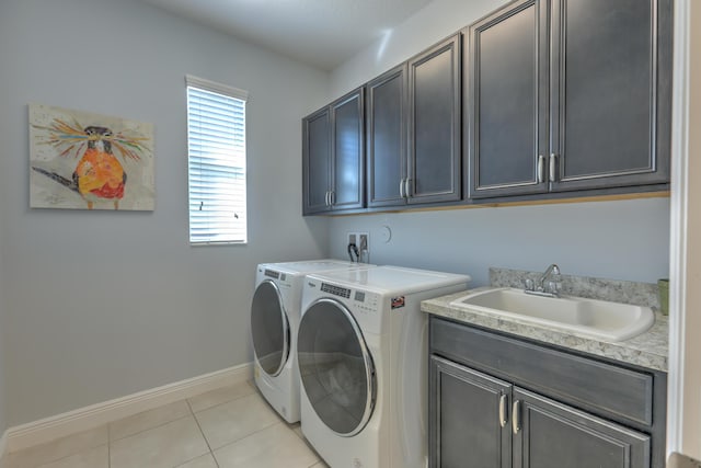 laundry area featuring independent washer and dryer, a sink, cabinet space, light tile patterned floors, and baseboards