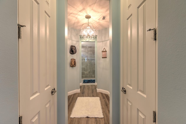 bathroom with a notable chandelier, baseboards, visible vents, and wood finished floors