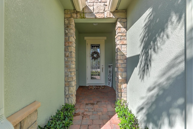 view of exterior entry featuring stucco siding and stone siding