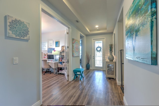 entryway with wood finished floors, visible vents, baseboards, a tray ceiling, and recessed lighting