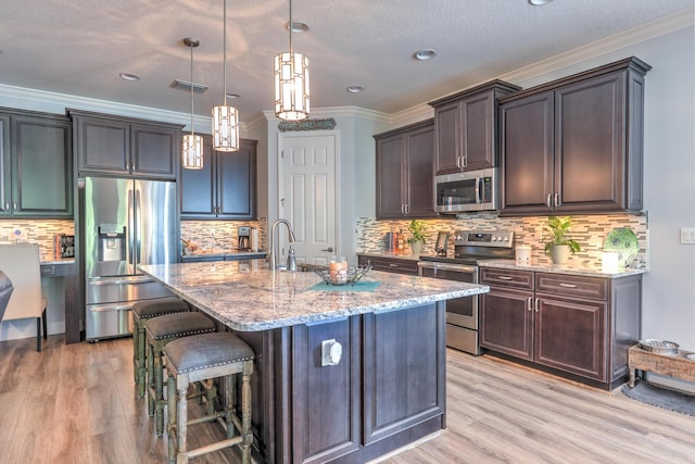 kitchen with light stone counters, a breakfast bar area, stainless steel appliances, and light wood-style flooring