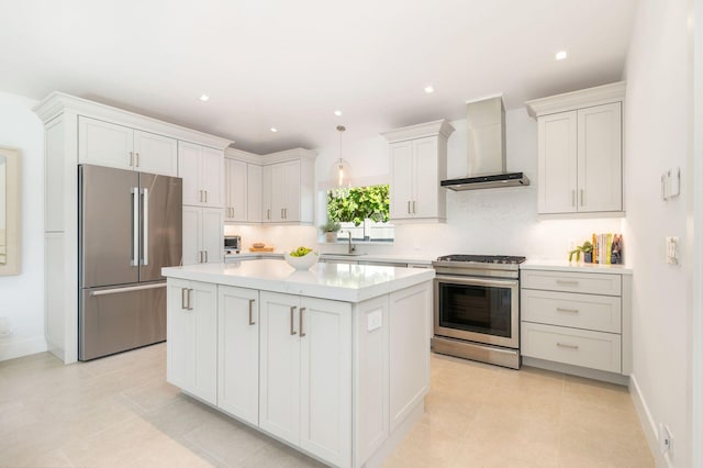 kitchen featuring a kitchen island, a sink, light countertops, appliances with stainless steel finishes, and wall chimney range hood