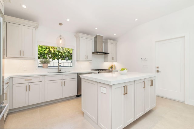 kitchen with a kitchen island, a sink, light countertops, decorative light fixtures, and wall chimney exhaust hood