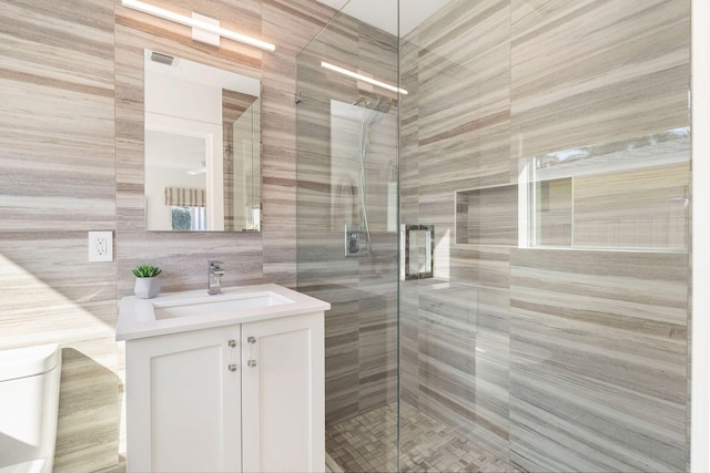 bathroom with visible vents, a shower stall, tile walls, decorative backsplash, and vanity