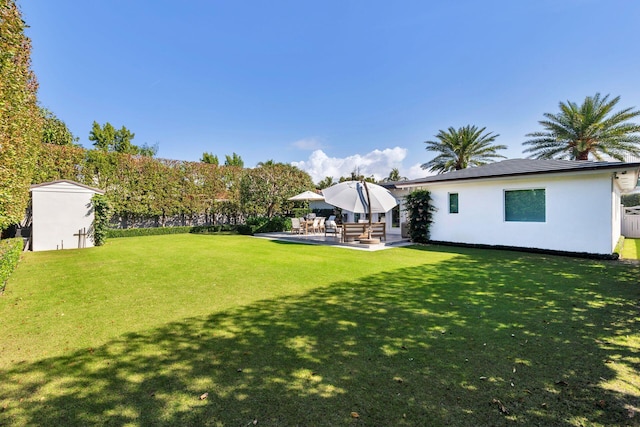 view of yard with an outdoor structure, a storage shed, and a patio