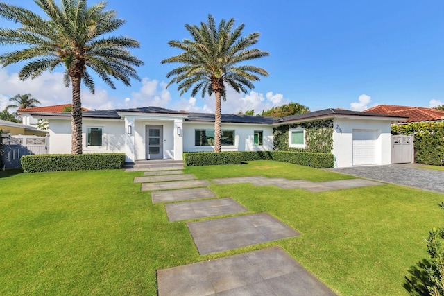 view of front of property with stucco siding, a front lawn, decorative driveway, fence, and a garage