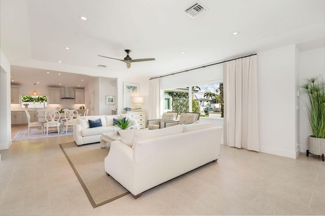 living area featuring light tile patterned floors, a ceiling fan, visible vents, baseboards, and recessed lighting