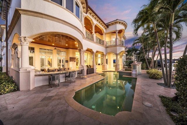 4216 Intracoastal Dr, Highland Beach, FL 33487 - back of property at dusk featuring a balcony, a patio, outdoor lounge area, stucco siding, and a pool with connected hot tub