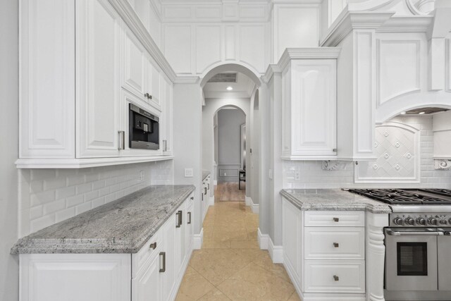 4216 Intracoastal Dr, Highland Beach, FL 33487 - kitchen featuring arched walkways, white cabinetry, tasteful backsplash, and high end range