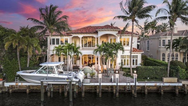 4216 Intracoastal Dr, Highland Beach, FL 33487 - back of house at dusk featuring a balcony, a water view, boat lift, and stucco siding