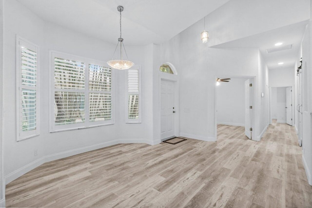 unfurnished dining area featuring light wood-style flooring, baseboards, and ceiling fan