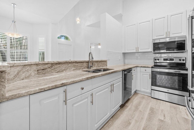 kitchen featuring a sink, stainless steel appliances, light stone counters, and tasteful backsplash