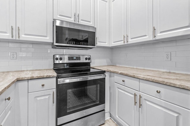 kitchen featuring backsplash, appliances with stainless steel finishes, white cabinetry, and light stone countertops