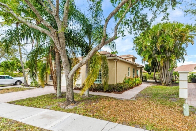 view of side of home featuring stucco siding, driveway, and a tile roof