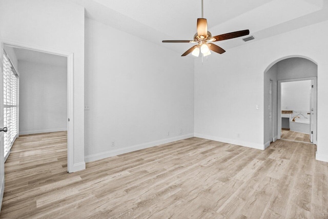 unfurnished room featuring visible vents, a ceiling fan, wood finished floors, arched walkways, and baseboards