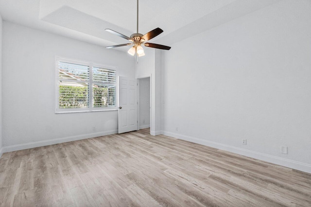 spare room featuring baseboards, ceiling fan, and light wood finished floors