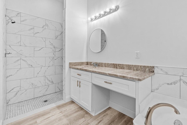 full bath featuring vanity, a bath, wood finished floors, and tiled shower