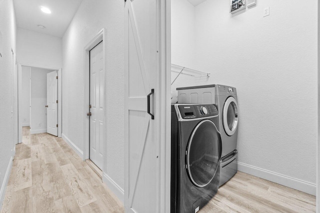 clothes washing area with laundry area, wood finished floors, independent washer and dryer, and baseboards