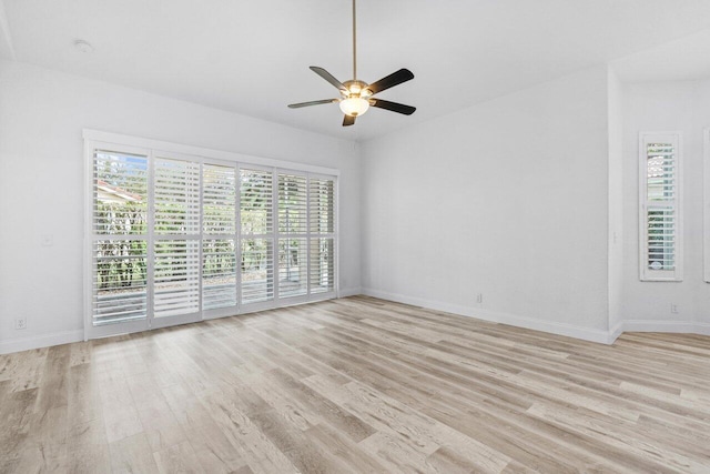 spare room with baseboards, light wood-style floors, and a ceiling fan