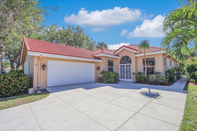 mediterranean / spanish-style home featuring stucco siding, an attached garage, and a tile roof