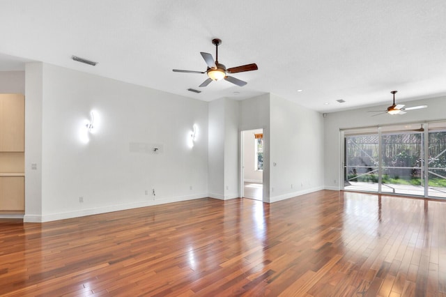 unfurnished living room featuring a ceiling fan, baseboards, visible vents, and wood-type flooring