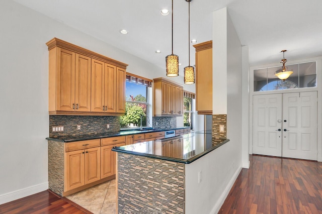 kitchen with baseboards, light wood-type flooring, a sink, pendant lighting, and tasteful backsplash