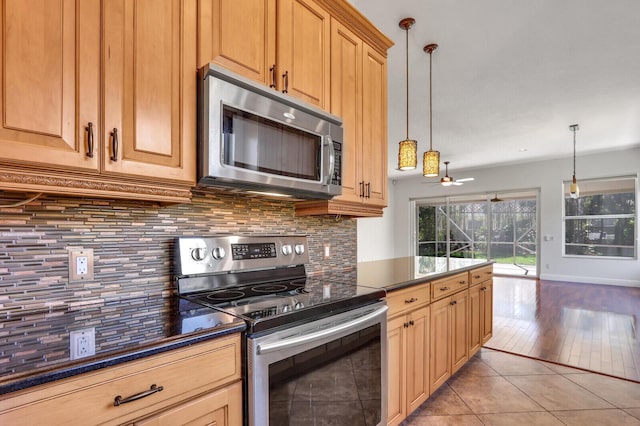 kitchen featuring light tile patterned floors, decorative backsplash, dark countertops, and appliances with stainless steel finishes