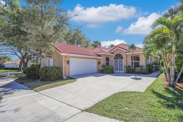 mediterranean / spanish-style house featuring a tiled roof, stucco siding, an attached garage, and concrete driveway