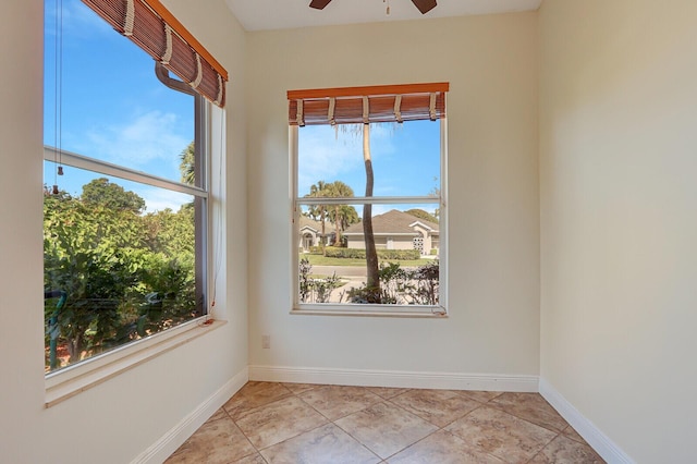 tiled spare room with a ceiling fan and baseboards