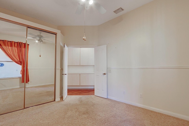 unfurnished bedroom featuring a ceiling fan, light colored carpet, visible vents, and baseboards