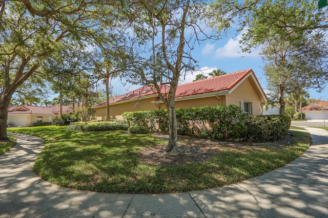 view of property exterior featuring stucco siding, a yard, and a tiled roof