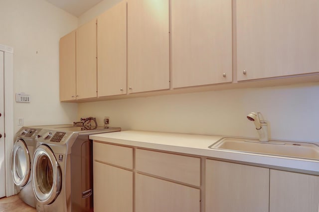 clothes washing area with separate washer and dryer, cabinet space, and a sink