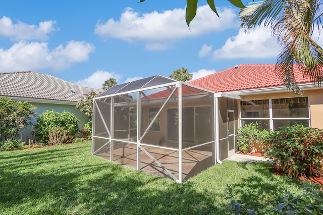 rear view of property with a lanai, a tiled roof, stucco siding, a yard, and a patio