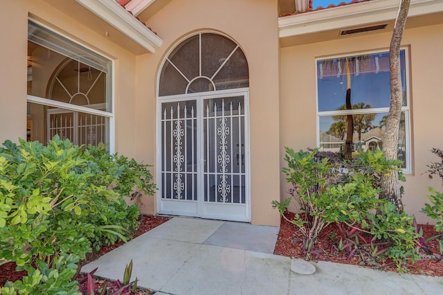 doorway to property with visible vents and stucco siding