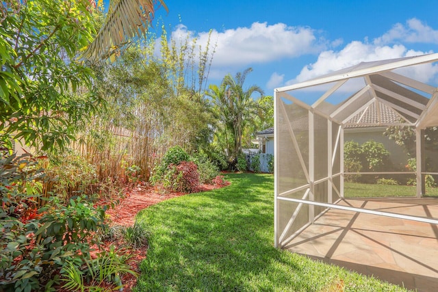 view of yard featuring glass enclosure and a patio