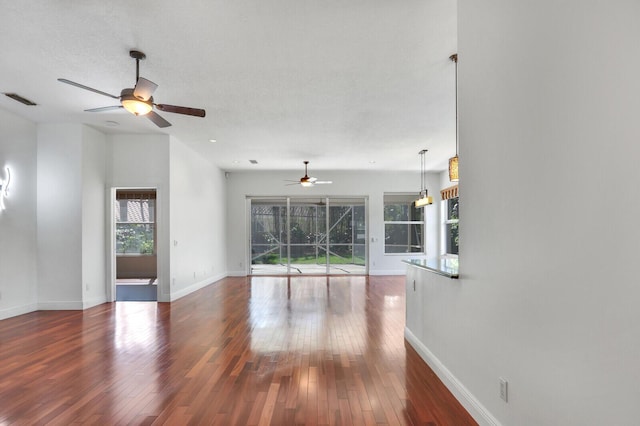 interior space featuring visible vents, ceiling fan, baseboards, and wood-type flooring