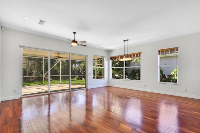 interior space featuring baseboards, wood-type flooring, visible vents, and a ceiling fan